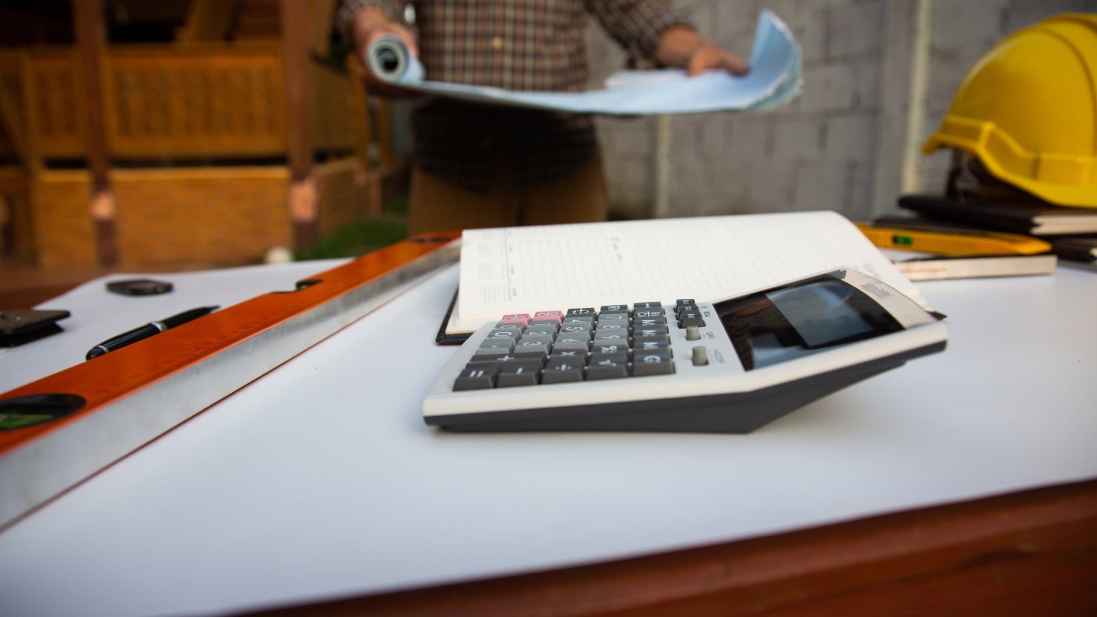 Calculadora y plano técnico de proyecto industrial sobre la mesa de un despacho
