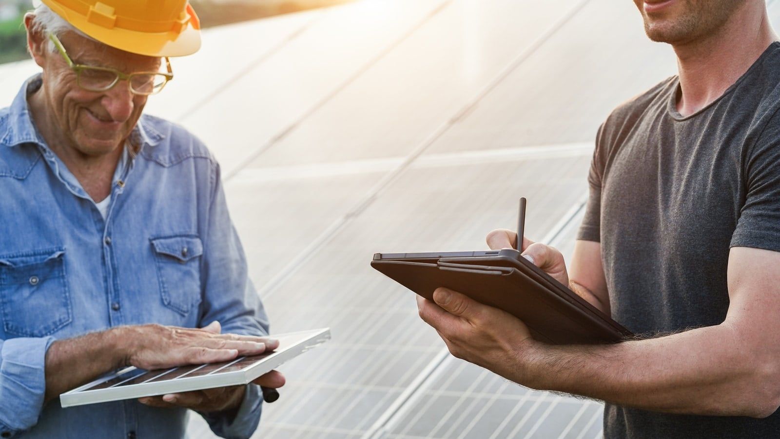 Equipo técnico de ingeniería revisando documentación junto a una instalación fotovoltaica industrial