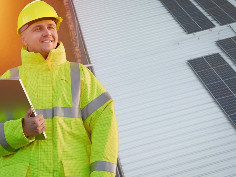Técnico solar realizando medición sobre cubierta industrial con array de placas